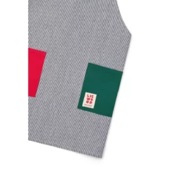 Nahaufnahme der gestreiften Arda-Schürze mit roter und grüner Tasche und kleinem Liewood-Etikett.