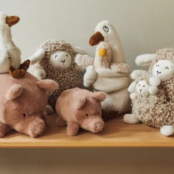 Schweinchen Spruce steht mit weiteren Liewood-Kuscheltieren auf einem Holzregal.