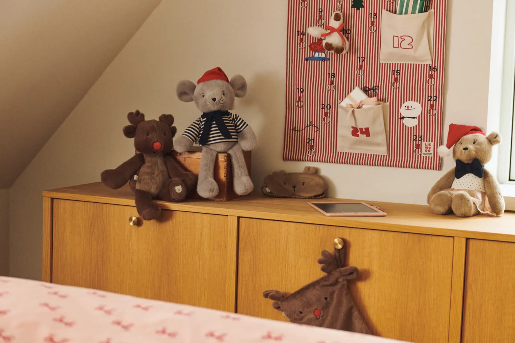 Weihnachtlich dekoriertes Kinderzimmer mit rosafarbenem Adventskalender, Kuscheltieren und Zeichenbrett.