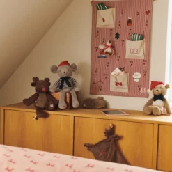 Blaise-Adventskalender an einer Holzwand über einer Kommode mit Kuscheltieren und einem Zora-Zeichenbrett.